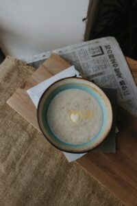 “Mingau de tapioca servido em tigela rústica de cerâmica, decorado com canela em pó e lascas de coco, sobre uma mesa de madeira, transmitindo aconchego e tradição da culinária amazônica.”