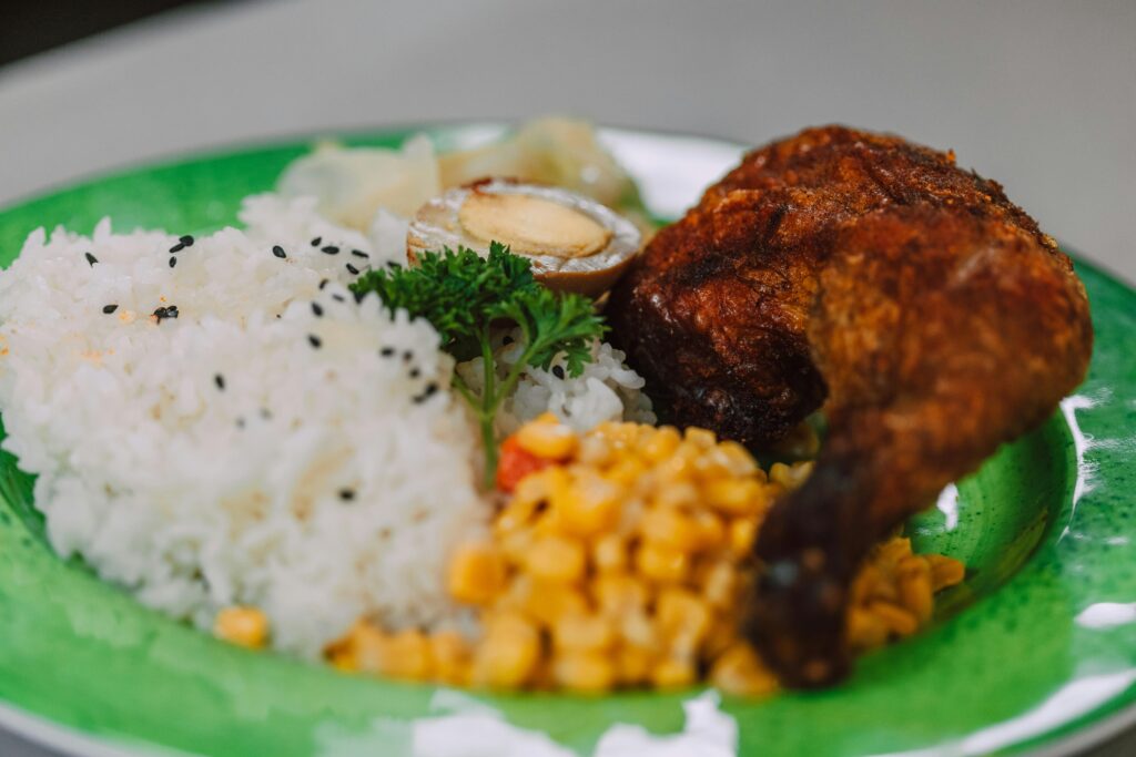 Cuscuz de tapioca tradicional nordestino servido em fatias, coberto com coco ralado fresco e leite condensado, sobre prato branco decorado com folhas verdes — sobremesa típica da culinária brasileira, especialmente popular nas festas juninas.