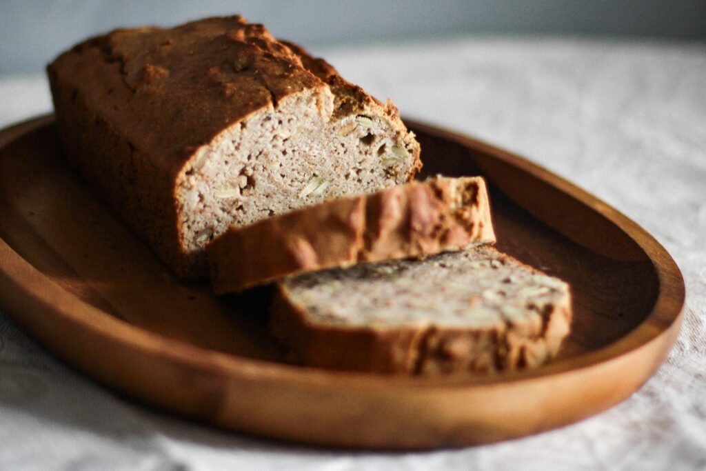 "Pão de macaxeira caseiro, dourado e macio, com crosta levemente crocante e interior fofinho, servido em fatias sobre uma tábua de madeira."